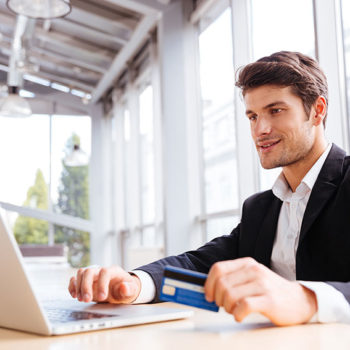 Young man working on a laptop in a bright office space.