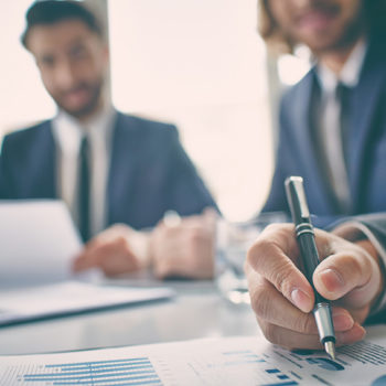 Two businessmen reviewing documents and charts in a meeting.