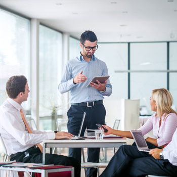 Business meeting with colleagues discussing ideas around a table.