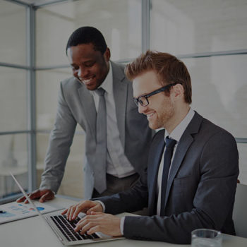 Two businessmen collaborating on a laptop in an office.