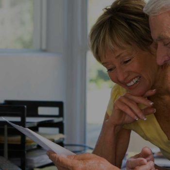 Older couple smiling while looking at a document together.
