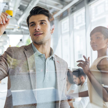 Business team brainstorming ideas using sticky notes on glass wall.