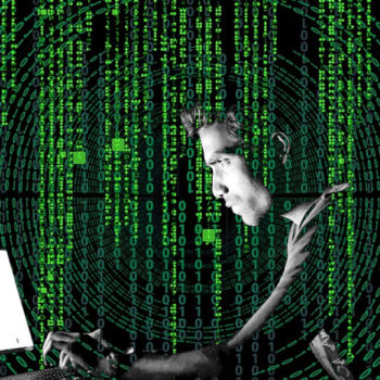 Hacker in a dark room with green code overlay on screen.