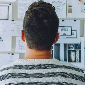 Man analyzing notes on a wall board.