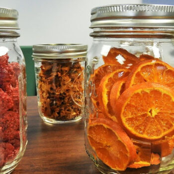 Jars of dried fruits on wooden table.