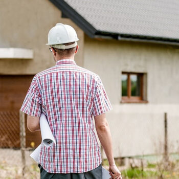 Man with blueprint outside modern house.