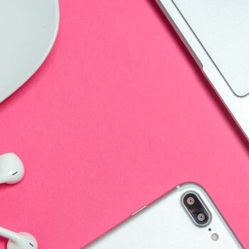 Coffee, laptop, phone, and earphones on desk.