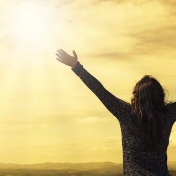 Person embracing sunlight with open arms.